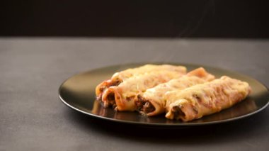 Siyah bir tabakta geleneksel Meksika enchiladosu. Sıcak yemek buharla gelir.