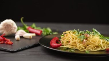 Bir adam masaya bir tabak makarna koyar. Koyu arkaplanda geleneksel İtalyan makarnası