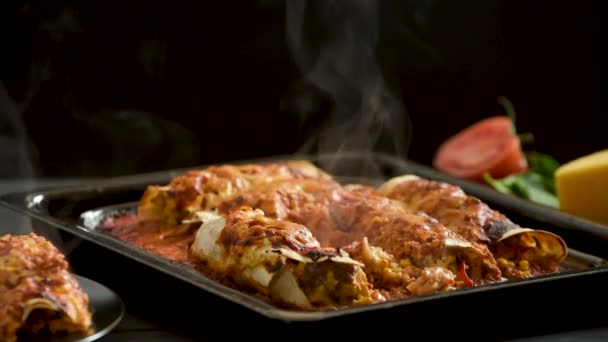 Cooked enchiladas on a black background goes steam — Stockvideo