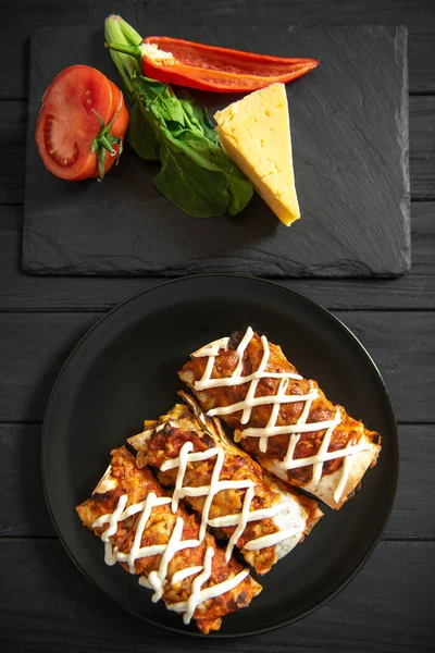 Cooked enchiladas on a black plate on a dark background. Top view — Photo