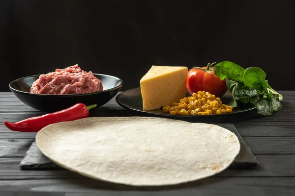 Pita with vegetables and meat on a black background. Cooking process — Photo
