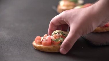 Bir erkeğin eli atıştırmalık bir şeyler alır. İtalyan bruschetta 'sı. Sağlıklı bir vejetaryen atıştırması..