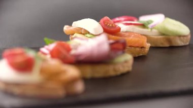 Masada aperatifler var. Domates peynirli ve fesleğenli klasik İtalyan bruschetta. Odak çerçeve boyunca sorunsuzca hareket eder.