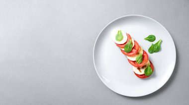 Dilimlenmiş domatesli İtalyan caprese salatası, mozzarella, fesleğen, mavi arka planda zeytinyağı. Üst görünüm, metin için yer