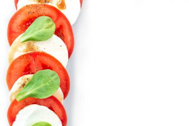 Fesleğen yapraklı gri tabakta Caprese salatası. İzole edilmiş. Peynirli ve domatesli İtalyan salatası. Avrupa Mutfağı.