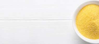 Beyaz bir kasede bir yığın polenta ya da mısır unu. Kurutulmuş mısır ya da mısır ezmesi. Üst manzara, fotokopi yeri. Sağlıklı gevrek kavramı.