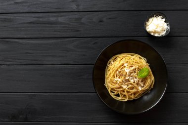 Geleneksel Roma makarnası. Siyah bir tabakta siyah arka planda klasik İtalyan makarnası. Uzayı kopyala Düz yatış ve üst görünüm