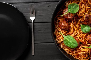 Soslu İtalyan makarnası ve köfteler servis için hazır. Yanında boş bir tabak var. Klasik İtalyan Spagettisi ve Et. Düz yatış ve üst görünüm