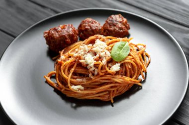 Klasik İtalyan makarnası. Kırmızı domates soslu spagetti köfte ve siyah tabakta fesleğen.