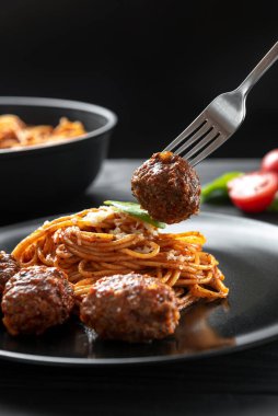 Köfteli çatal. Siyah tabakta köfteli makarna..