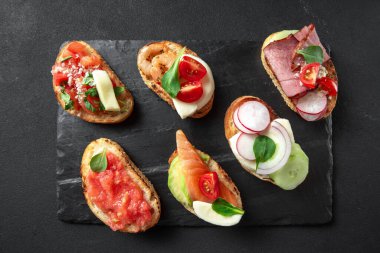 Karanlık bir arka planda sandviçler. Ana yemekten önce bir aperatif. Üst Manzara. Hughchetta koyu bir arkaplan üzerine kurulu. İtalyan aperatifi.