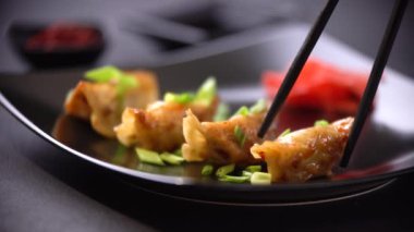 Bir adam Asya yemeği yiyor. Japon usulü kızarmış hamur köftesi, Gyoza adamı çubuklarla yer..