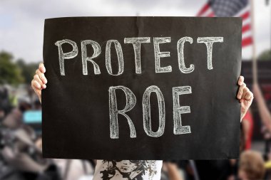 A womans hands hold a Protect ROE banner. a woman stands up for her rights with a banner at a rally. The concept of protests in the United States. Fighting for the rights of women and feminists. Los