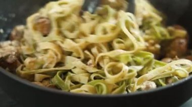 Klasik İtalyan fettuccini alfredo pastası krema soslu ve tavada mantarlı. Erişte Pişirme Süreci. Geleneksel bir İtalyan ve Roma yemeği, tavada ıspanaklı ve mantarlı fettuccini makarna.