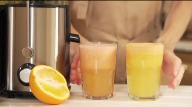 Bir kadının elleri meyve sıkacağında hazırlanmış iki bardak taze meyve suyu alır. Greyfurt ve portakal suyu sağlıklı gıdalar, diyet için meyveler ve vücudun zehirlenmesinden arınmasıdır. Bir içki hazırlıyorum.