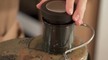 Meyve sıkacağında meyve suyu yapıyorum. Yakın plan. Taze meyve suyu hazırlıyorum. Meyve sıkacağı ve meyve sıkacağı ile meyve sıkma makinesini birbirine yakın tut. Meyveleri meyve sıkacağı ev mutfağına iterek.