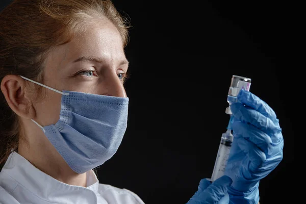 A female doctor draws a vaccine or medicine into a syringe. The nurse draws the vaccine, flu medication and diseases into the syringe.