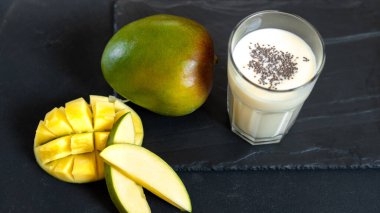 Siyah arka planda, mangolu süt içeceği. Klasik bir mango milkshake 'i, Lassi. Hindistan 'da Chia tohumlu geleneksel bir içecek. Siyah arkaplandaki zerdeçal lassie ya da mango lassi kopyası