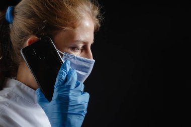 A distraught and depressed female doctor speaks to a patient over the phone. A doctor talks on the phone about a bad diagnosis. A female doctor or nurse is on the phone saying bad news, test results