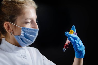 Sağlık çalışanı geç saatlere kadar çalışan bir doktor ya da hemşiredir. Kadın bir doktor elinde test tüpleri tutuyor ve onları inceliyor..
