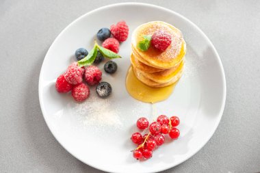 Açık arkaplanda pudra şekerli ve ballı krep. Vejetaryenler için sağlıklı beslenme. Tüm aile için bir kahvaltı. Üst görünüm
