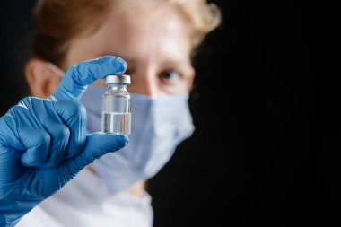 Kadın bir doktor siyah arka planda bir tüp ilaç tutuyor. Bir hemşire elinde bir ilaç tutuyor. Şişeye odaklan. Covid-19 'un yeni versiyonu, Omicron. Koronavirüsün Omicron varyantı
