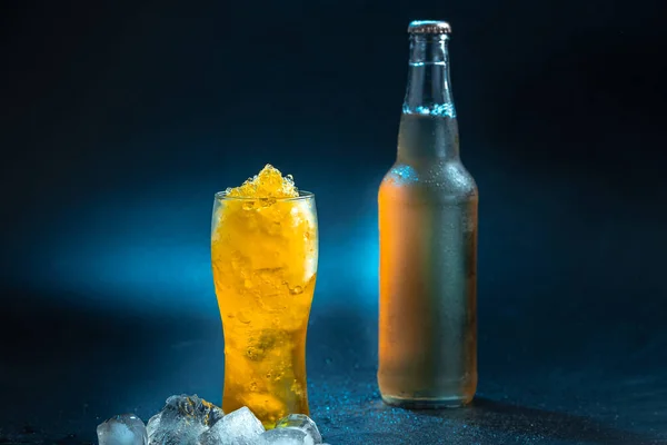 Beer slushies cocktail. Beer with ice. Summer drink frozen beer grinded into ice chips. Cocktail on black background with a bottle of beer.