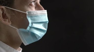 doctor or nurse crying against a black background. The health care worker is upset and tears are flowing. The concept of the doctors hard work in the clinic.