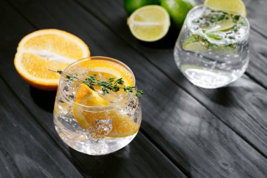 two glasses with an alcoholic cocktail on a wooden dark background. hard seltzer is a low-alcoholic drink. Strong seltzer cocktails with lime. Alcoholic cocktail tonic clear. hard seltzer is a low
