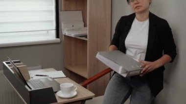 Real life in the office. A girl manager is working with documents and a folder almost falls out of her hands. Laughs at a funny situation in the office. Funny moments in the office.