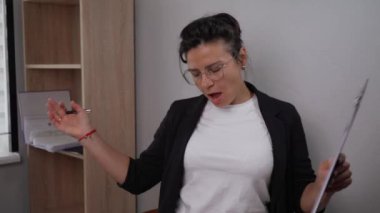 Young woman in office workers glasses dancing in the workplace, woman dancing in the office. Ordinary workdays can be joyful. Real office real life