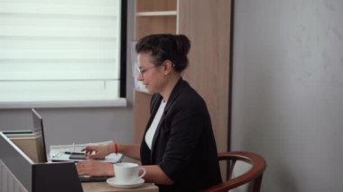 A girl is excited about selling on a cryptocurrency exchange and other online betting. A delighted young Caucasian woman wearing glasses looks at her phone screen, celebrating receiving an email with