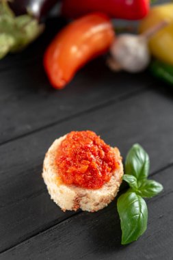 Ayvar 'la kadeh kaldıralım. Ahşap arka planda pişmiş tatlı biber aperatifi. Hazırlık malzemeleri yan yana uzanıyor. Ayvar Balkan yemeği, sebze havyarı, kavrulmuş kırmızı çan macunu.