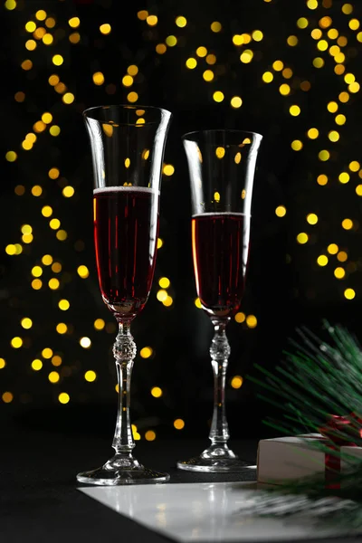 New Years Eve 2022 - Champagne glass on a dark background with a side of garlands. A classic alcoholic beverage for a New Years Eve holiday atmosphere. Vertical photo