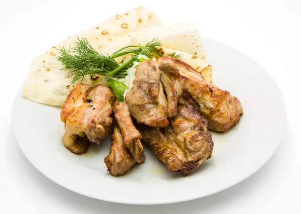 Izgarada kızarmış domuz kaburgası ve beyaz bir tabakta pide.