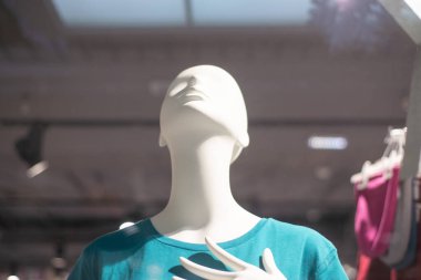 Mavi tişörtlü bir vitrindeki mankenler yukarı bakıyor.