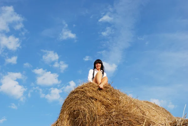 Woman on hay bale in summer field — Stock Photo, Image