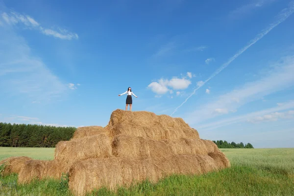 Woman on hay bale in summer field — Stock Photo, Image