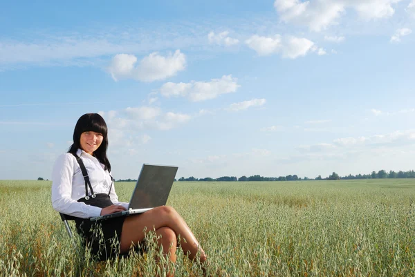 Attractive young girl working on computer in green field — Stock Photo, Image