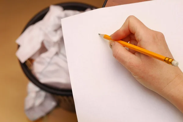 Рука держит желтый карандаш на белой бумаге — стоковое фото