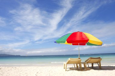 sandalye ve renkli kum plaj şemsiyesi