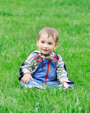yeşil çim oturan sevimli bebek