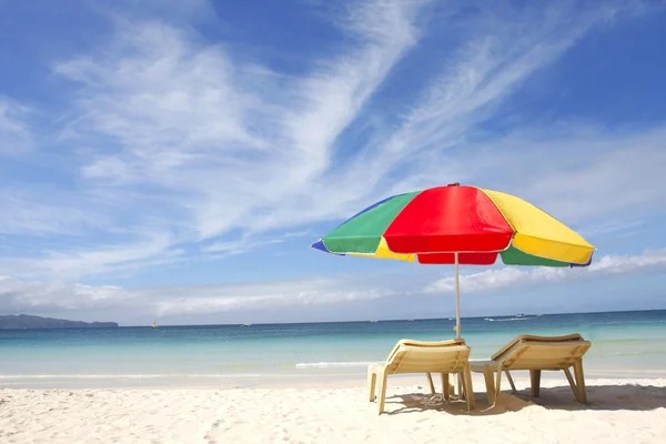 Liegestühle und bunter Sonnenschirm am Sandstrand — Stockfoto