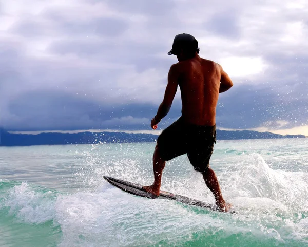 Jeune homme chevauchant un wakeboard dans des gouttes d'eau — Photo