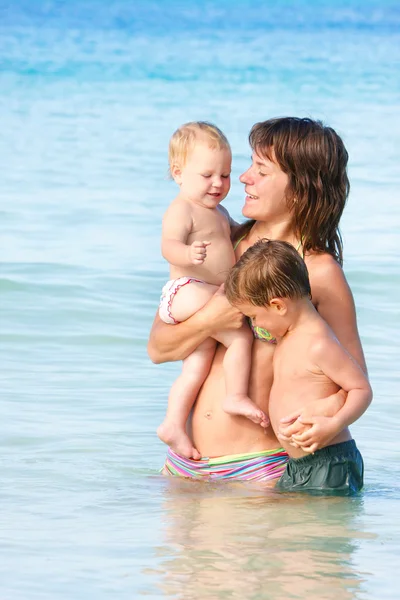 Glückliche Mutter mit zwei Kindern, die im Wasser spielen — Stockfoto