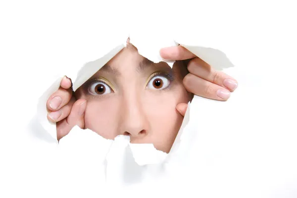 Young girl peeping through hole in white paper — Stock Photo, Image