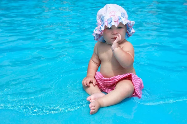 Meisje van de baby in hoed zitten waterpool — Stockfoto