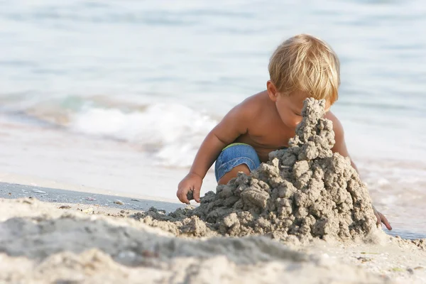 Menino brincando com areia na praia — Fotografia de Stock