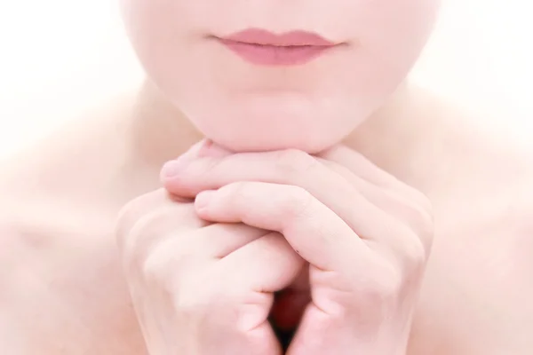 Närbild på kvinnliga läppar och korsade händer över vita — Stockfoto