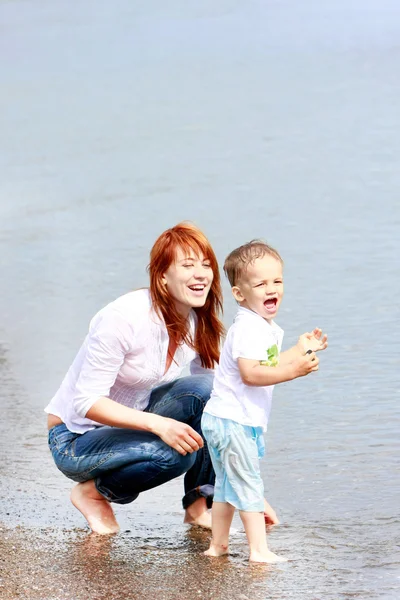 Счастливая мать и сын на пляже — стоковое фото